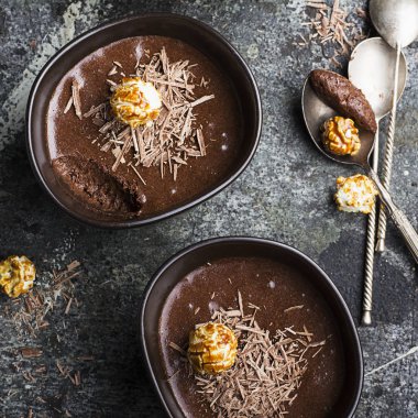 Hassas tatlı çikolata mousse çikolata yaptı rahat bir sonbahar cips ve porselen karanlık içinde karamelli patlamış mısır basit bir gri taş zemin üzerinde kase. Üstten Görünüm.