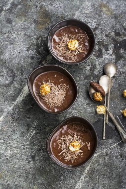 Hassas tatlı çikolata mousse çikolata yaptı rahat bir sonbahar cips ve porselen karanlık içinde karamelli patlamış mısır basit bir gri taş zemin üzerinde kase. Üstten Görünüm.