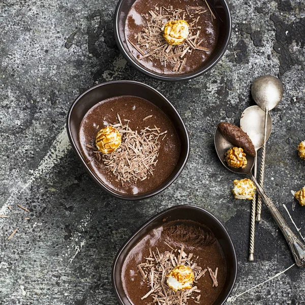 A hangulatos őszi készült finom desszert csokoládé mousse, csokoládé chips, és porcelán sötét karamell popcorn tálat egy egyszerű szürke kő háttér. Szemközti nézet. — Stock Fotó