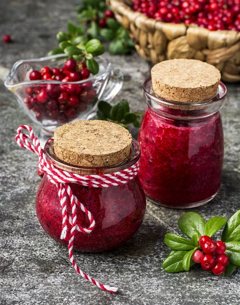 Puree z borówkowo Północnej dzikim lesie, żurawinowy do zdrowej diety organicznej w małym szklanym porcje słoiki z jagód i pozostawia na szarym tle kamienia. Selektywny fokus. — Zdjęcie stockowe