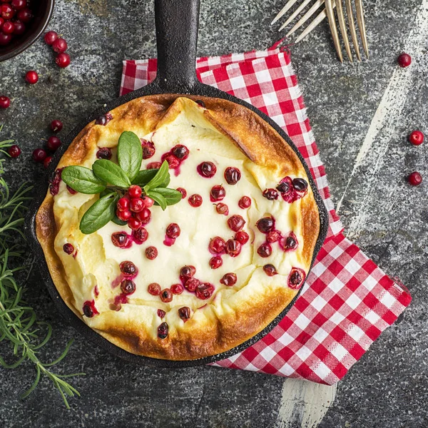 Hemmagjord anbud ostmassa gryta med saftiga bär tranbär på en grå sten bakgrund med gafflar och grenar av bär. Ovanifrån. — Stockfoto