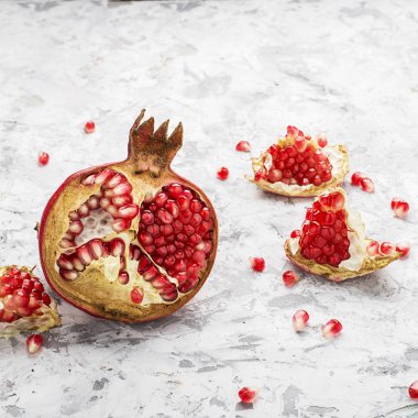 Arka planda dağınık tahıllar ile hafif bir mermer zemin üzerine olgun pembe nar yarısı. Tedarik tasarım için. Üstten Görünüm.