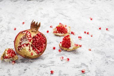 Arka planda dağınık tahıllar ile hafif bir mermer zemin üzerine olgun pembe nar yarısı. Tedarik tasarım için. Üstten Görünüm.