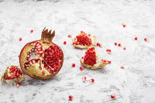Arka planda dağınık tahıllar ile hafif bir mermer zemin üzerine olgun pembe nar yarısı. Tedarik tasarım için. Üstten Görünüm.