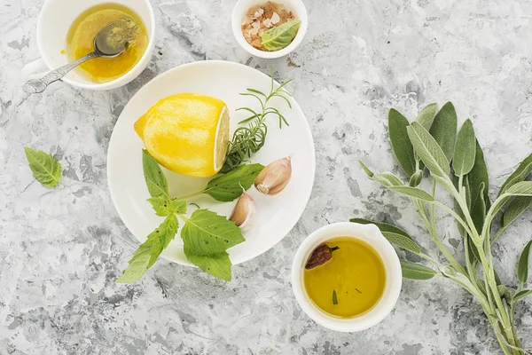 Ingrediënten voor de huisgemaakte citroen saus vinaigrette dressing voor de salade met olijfolie, zout, peper, citroensap, citroenschil, SAP, knoflook en kruiden naar smaak. Bovenaanzicht op een lichte achtergrond. — Stockfoto