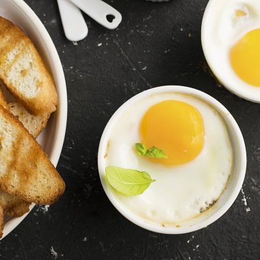 İki kişilik kahvaltı. Yumurta pişmiş fırında kızarmış ekmek ile seramik alakart formları ve taze salatalık dilimleri. Üstten Görünüm.
