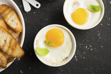 İki kişilik kahvaltı. Yumurta pişmiş fırında kızarmış ekmek ile seramik alakart formları ve taze salatalık dilimleri. Üstten Görünüm.