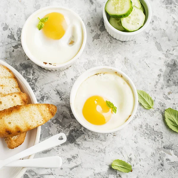 İki kişilik kahvaltı. Yumurta pişmiş fırında kızarmış ekmek ile seramik alakart formları ve taze salatalık dilimleri. Üstten Görünüm.