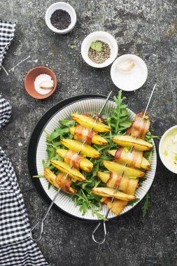 Fırında pişmiş jambon dilimleri içinde patates dilimleri ile iştah açıcı şişleri yoğurt ve yeşil salata ile servis. Üstten Görünüm.