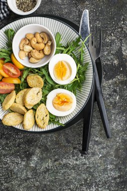 Haşlanmış yumurta, roka, salata, domates, pecans ve gevrek ekmek kruton gri bir arka plan üzerinde büyük bir tabak taze bahar salatası. Üstten Görünüm..