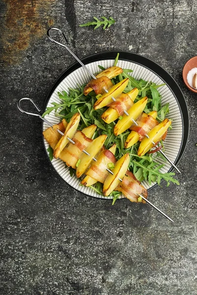 Aptitretande spett med potatisskivor i bacon skivor bakad i ugn serveras med yoghurt och en grönsallad. Ovanifrån. — Stockfoto