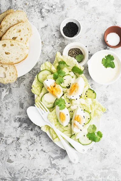 Salade de jardin aux œufs au curry avec laitue, tranches de concombre frais, sauce au curry à base de yaourt, œufs bio au sésame noir et herbes vertes. Vue du dessus . — Photo