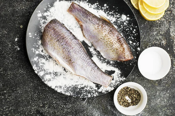 Frisch entkernte geschnittene Flussfische vor dem Kochen mit Salz, Pfeffer, Zitronenscheiben auf grauem Grunge-Hintergrund. Ansicht von oben. — Stockfoto