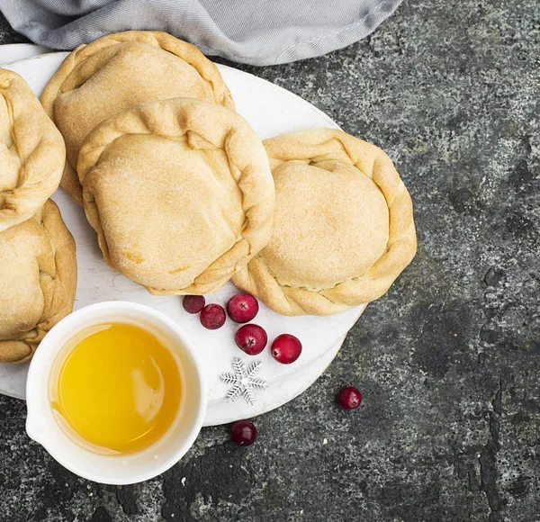 Bequemes Essen für die ganze Familie. hausgemachte Mini-Kuchen aus frischem einfachen Teig mit saisonalen Beeren, serviert mit Honig. Draufsicht auf grauem Grunge-Hintergrund. — Stockfoto