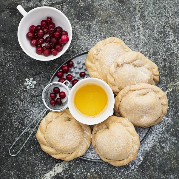 Comfortabele voedsel voor het hele gezin. Zelfgemaakte mini taarten gemaakt van verse eenvoudig deeg met seizoensgebonden bessen, geserveerd met honing. Bovenaanzicht op een grijze grunge achtergrond. — Stockfoto