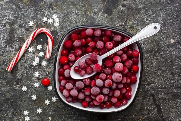 Frozen cranberries in a white enameled vintage bowl on a plain gray background with a beau enameled spoon. Top View. — Stock Photo, Image