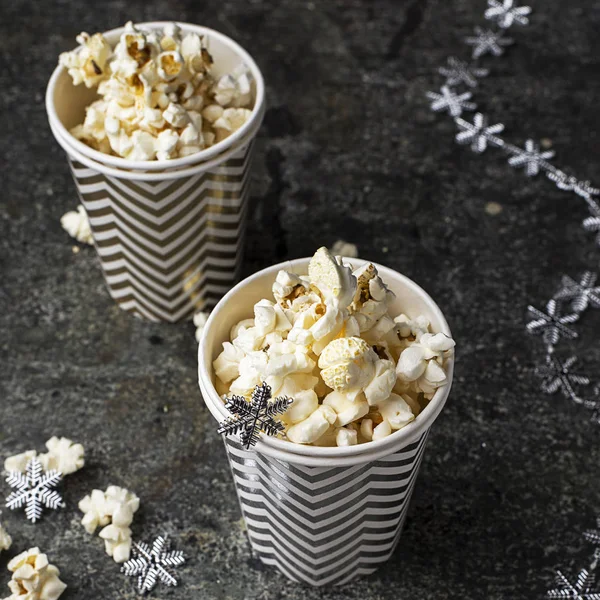 Popcorn in papier grijs witte kerst cups voor winter vakantie vergaderingen met vrienden met New Year's Christmas decor, sterren op een grijze grunge achtergrond. Bovenaanzicht. — Stockfoto