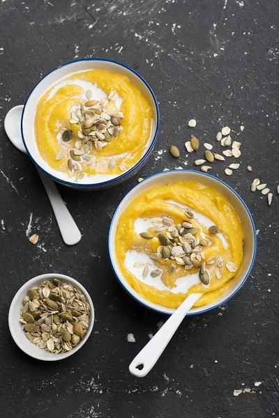 Sopa de calabaza y sidra de manzana con una cobertura de semillas de calabaza tostadas crujientes, semillas de girasol y copos de avena, albahaca púrpura en un tazón de servir sobre un fondo claro. Vista superior . — Foto de Stock