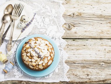 Badem ahşap arka plan hizmet Paskalya ile yaprakları ile dekore edilmiş basit ev yapımı turta kullanılan mavi ve sarı renkler, bıldırcın yumurtası, lavanta çiçekleri, vintage keten masa örtüsü el yapımı.