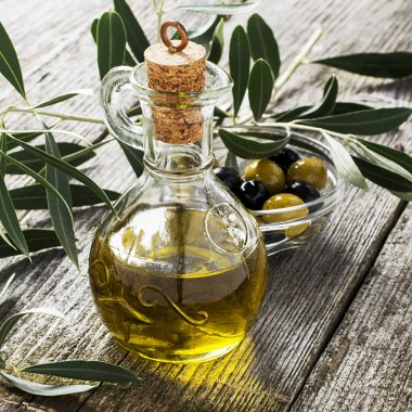 Zeytin ve zeytin ağacı dalları tarafından çevrili zeytin kesme tahtası üzerinde sızma zeytinyağı ile sürahi. Seçici odak. Sağlıklı doğal gıda kavramı