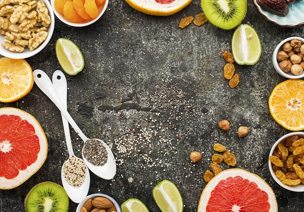 Ljusa hälsosamma ingredienser för rätt kost: frukter, nötter, bär, superfood, apelsin, grapefrukt, mandlar, torkade aprikoser, fikon, datum, russin, valnötter, chiafrön, quinoa. Ovanifrån. — Stockfoto