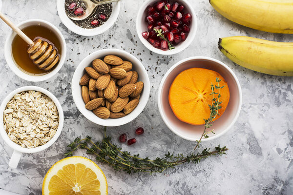 Ингредиенты для здорового завтрака, орехи, овсянка, мед, ягоды, фрукты, черника, апельсин, семена граната, миндаль, грецкие орехи Концепция натуральных органических продуктов питания в сезон. Вид сверху
