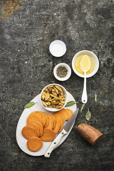 Ingredienser för matlagning hälsosam enkla snacks från skivor av sötpotatis, valnötter med honung innan bakning. Ovanifrån. På grunge grå bakgrund. Kopiera utrymme — Stockfoto