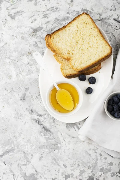 Pão de trigo branco caseiro fresco para um lanche com mel de limão floral fresco em um prato branco em um fundo claro. Vista superior. Espaço de cópia . — Fotografia de Stock