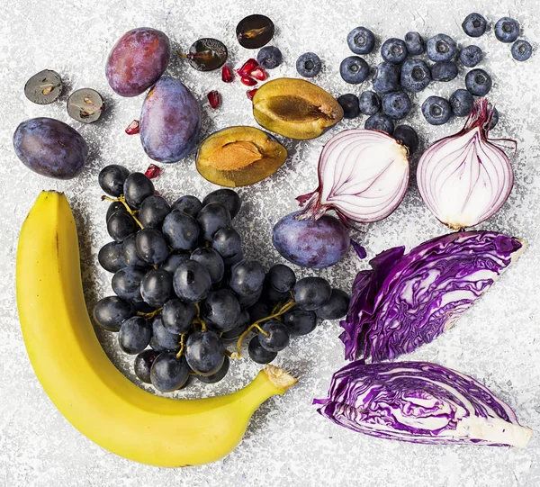 Verduras y frutas ricas en vitamina antocianina: plátanos, arándanos, col roja, cebollas moradas dulces, uvas negras, ciruelas pasas. Beneficios de la nutrición para el corazón y el sistema cardiovascular. Vista superior . —  Fotos de Stock