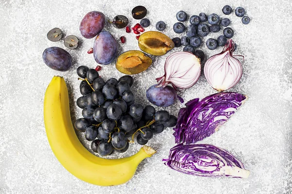 Verduras y frutas ricas en vitamina antocianina: plátanos, arándanos, col roja, cebollas moradas dulces, uvas negras, ciruelas pasas. Beneficios de la nutrición para el corazón y el sistema cardiovascular. Vista superior . —  Fotos de Stock