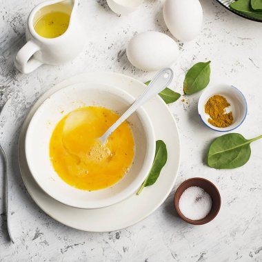 Ispanak ve zerdeçal arka planda ile çırpılmış yumurta için malzemeler. Üstten Görünüm. Kopya alanı.