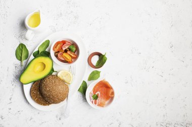 Sağlıklı Kahvaltı: Mısır gevreği rulo somon, kiraz domates, ıspanak, avokado. hafif bir arka plan üzerinde yaban mersini. Üstten Görünüm. Kopya alanı.