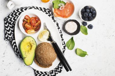 Sağlıklı Kahvaltı: Mısır gevreği rulo somon, kiraz domates, ıspanak, avokado. hafif bir arka plan üzerinde yaban mersini. Üstten Görünüm. Kopya alanı.