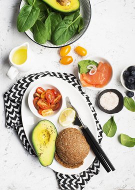 Sağlıklı Kahvaltı: Mısır gevreği rulo somon, kiraz domates, ıspanak, avokado. hafif bir arka plan üzerinde yaban mersini. Üstten Görünüm. Kopya alanı.