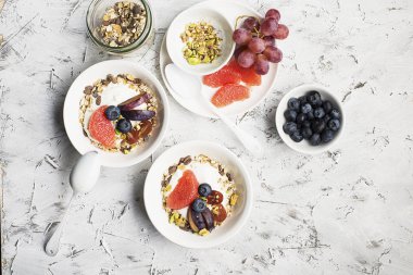 Mevsimlik sağlıklı kahvaltı: yoğurt, çikolata granola, Pembe greyfurt, üzüm, fıstık. Üstten Görünüm. Uzay kopyalayın. düz lay