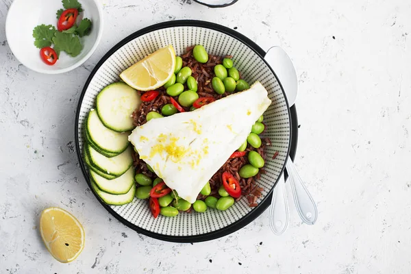 Filetes jugosos de pescado blanco al vapor sobre un cojín de arroz fragante rojo y verduras frescas: soja, pimiento, limón. Vista superior . —  Fotos de Stock