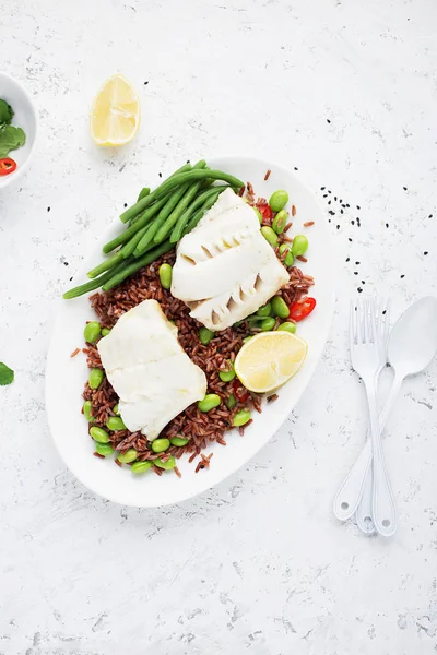 Filetes jugosos de pescado blanco al vapor sobre un cojín de arroz fragante rojo y verduras frescas: soja, pimiento, limón. Vista superior . —  Fotos de Stock