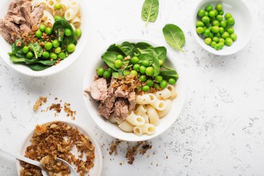 Ton balığı makarna kasesi salatası. Taze ıspanak, taze bezelye ve ekmek kırıntılarıyla. Üst Manzara. Düz yatıyordu