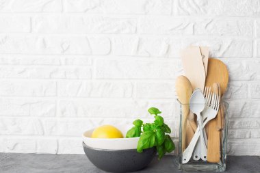 Basit minimalist mutfak rafı. Çatal bıçak takımı, mutfak aletleri, bardakta yeşiller, arka planda meyveler. Scandy tarzı. Ev konforu,