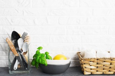 Basit minimalist mutfak rafı. Çatal bıçak takımı, mutfak aletleri, bardakta yeşiller, arka planda meyveler. Scandy tarzı. Ev konforu,