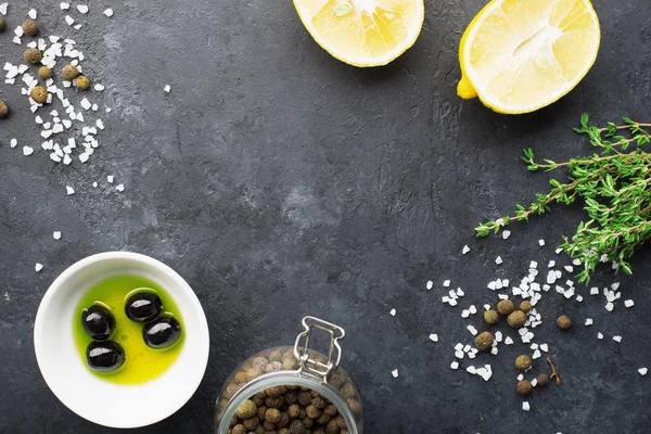 Pozadí černého potravinového rámu s čerstvými aromatickými bylinkami a kořením, kopírovací prostor, horní pohled. Nové koření, tymián, citron, olivy na tmavém pozadí — Stock fotografie