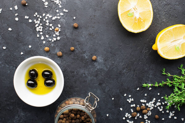 Фон рамы черной пищи со свежими ароматическими травами и специями, пространство для копирования, вид сверху. Оллспейс, тимьян, лимон, оливки на темном фоне
