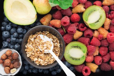 Sağlıklı bir kahvaltı için gerekli malzemeler. Beslenme, granola, yulaf ezmesi, fındık, meyve, meyve, kivi, muz, ahududu, yabanmersini, tohum, elma. Vitamin ve lif açısından zengin bir diyet. Üst görünüm