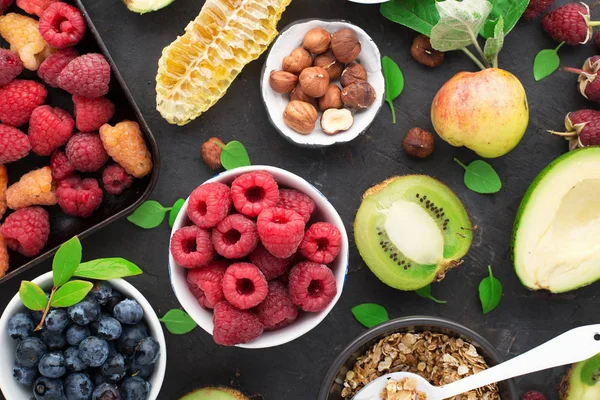 Ingredienser för en hälsosam frukost. Näring, granola, havregryn, nötter, frukter, bär, kiwi, bananer, hallon, blåbär, frön, äpplen. En kost rik på vitaminer och fibrer. Ovanifrån — Stockfoto