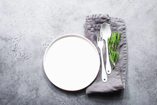 Tabel mengatur piring putih, sendok putih dan garpu berlapis putih pada latar belakang modern abu-abu. Dengan serbet abu-abu linen. Kecenderungan sejati Monokrom. Gaya minimalisme. Tampilan atas — Stok Foto