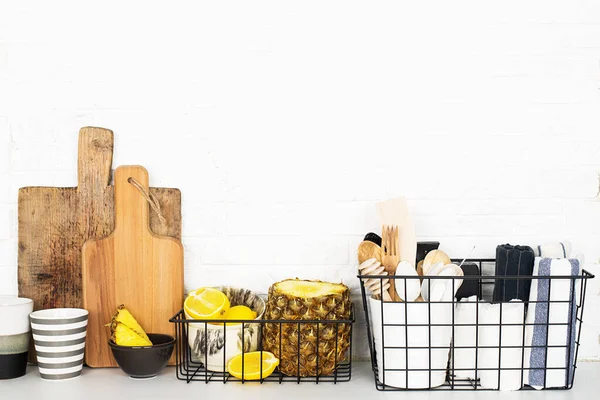 Mutfak raf beyaz arka plan, taze limonlar, ananas, mutfak aletleri, aletler, doğrama tahtaları, depolama sepetleri. Çevre dostu bir hayat. Ev tarzı, minimalizm, sağlıklı beslenme.
