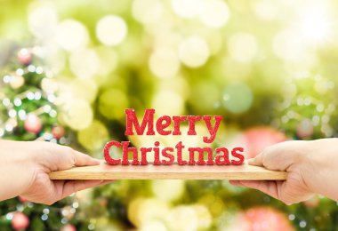 Neşeli Noel kırmızı glitter numarası ile ahşap plaka tutan el 