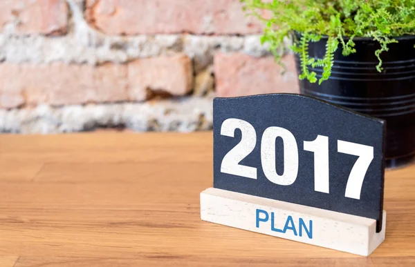 New year 2017 number on blackboard sign and green plant on wood — Stock Photo, Image