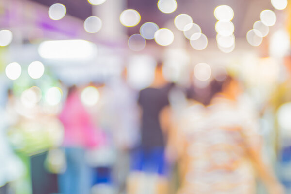 Blurred background: crowd of people in expo fair with bokeh ligh