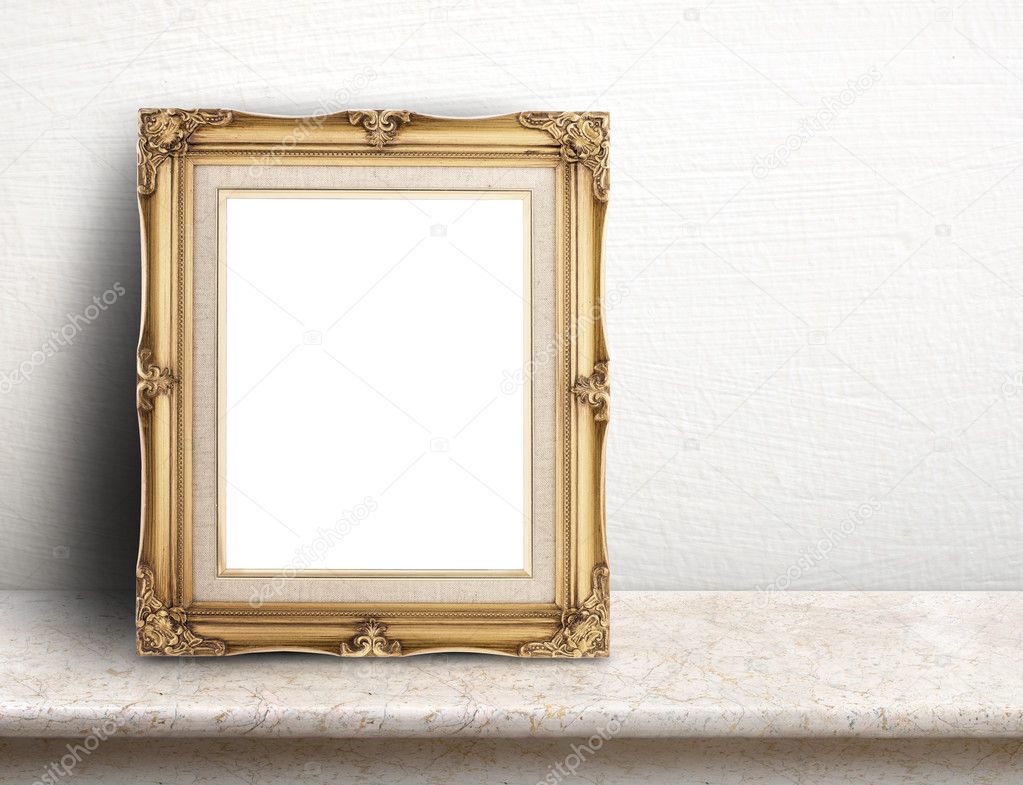 Blank Gold victorian picture frame on cream marble table at whit
